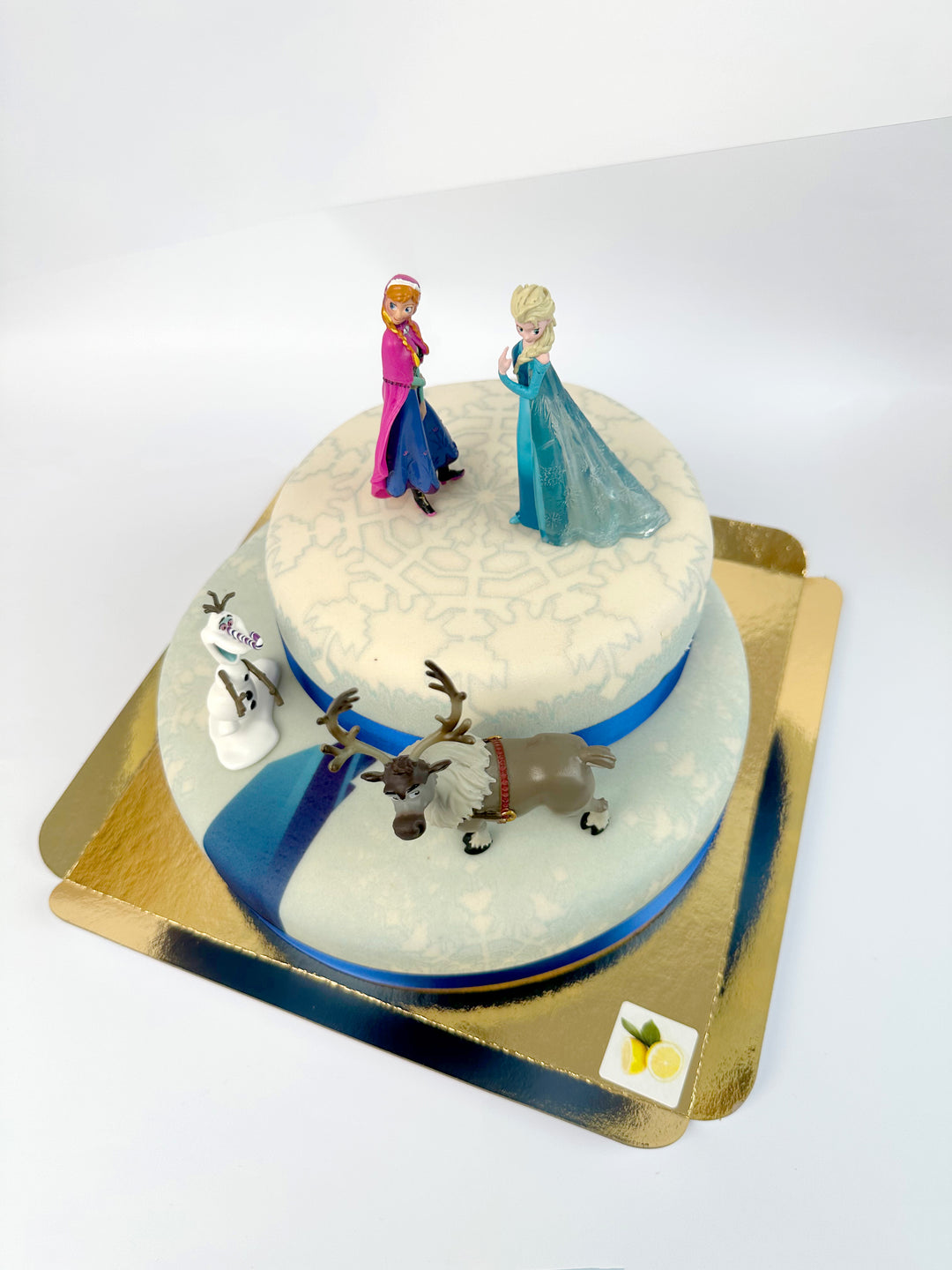 Frozen® Elsa, Anna & Olaf figures on a 2-tier snowflake cake