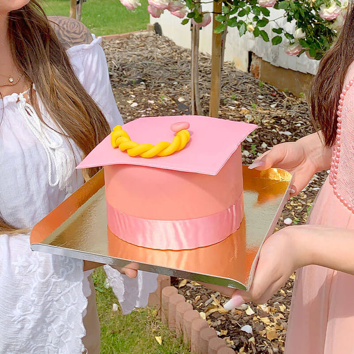 Graduation cake in the shape of a pink graduation cap